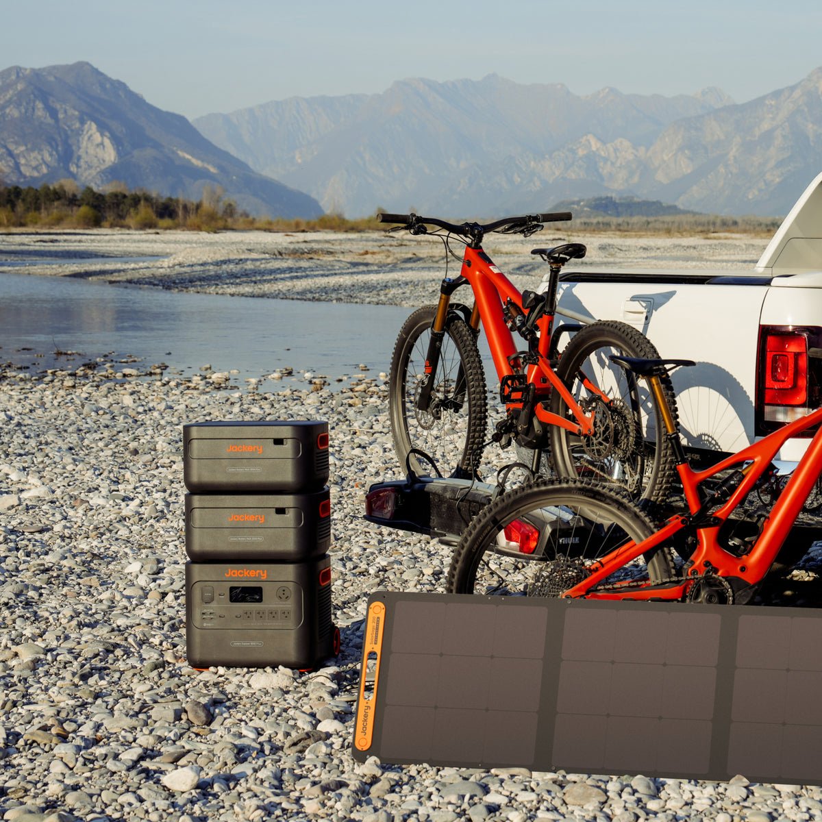 Jackery Explorer and SolarSaga on a riverbank with bikes and a truck